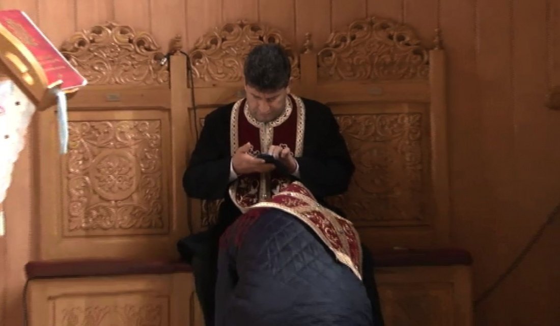  VIDEO: Cât de mult îi pasă acestui preot de enoriașii săi? Filmat când butona telefonul în timpul spovedaniei