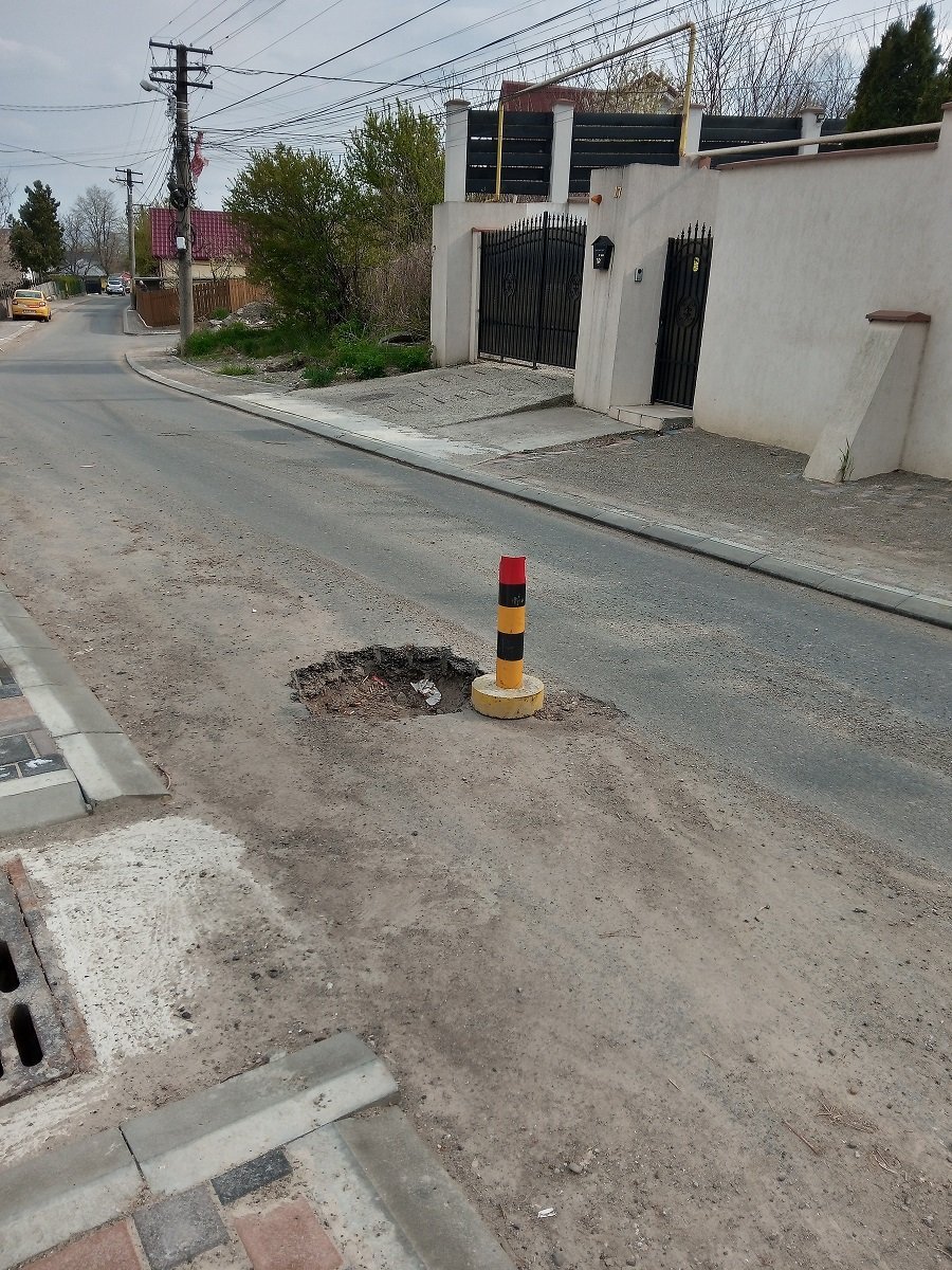 FOTO: Groapă în asfaltul nou, semnalizată de o lună cu un popic pe strada Țicău