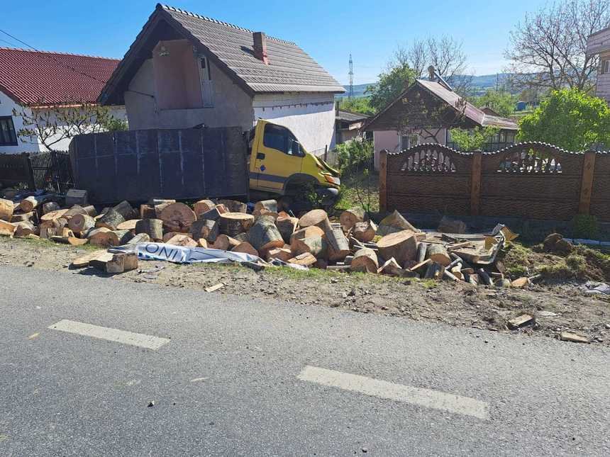  O autoutilitară care transporta material lemnos s-a răsturnat în curtea unei case
