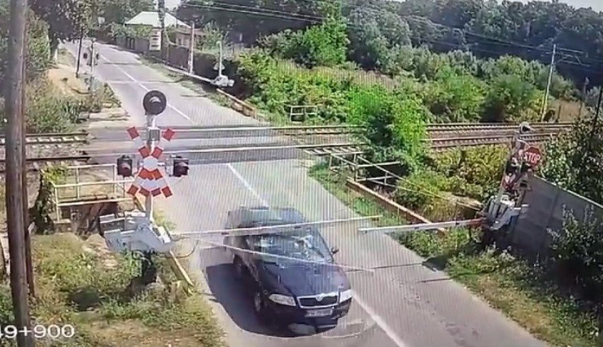  Şofer filmat în timp ce forţează şi rupe bariera chiar înainte de trecerea la nivel cu calea ferată